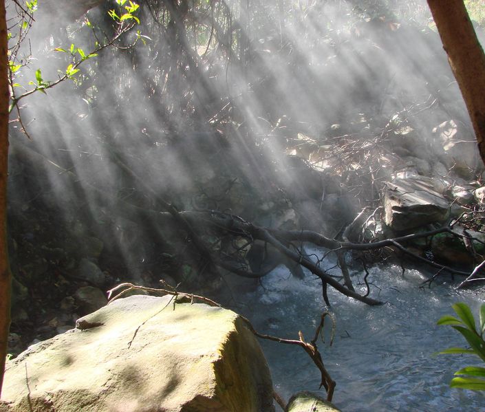 Zonnestralen boven een kokende warmwaterbron in het park Rincon de la Vieja
