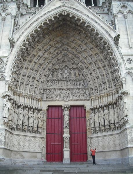 Nietig mens maakt detailfoto in het hoofdportaal van de katedraal.
